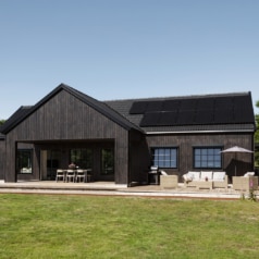 The black timber Kronås home, with patios opening onto the garden
