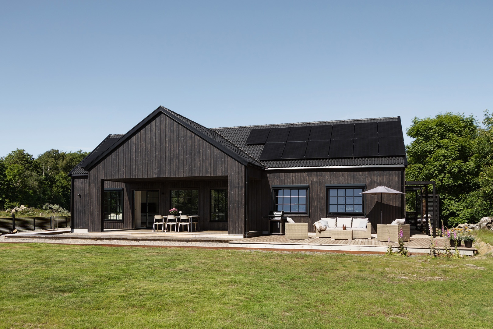 The black timber Kronås home, with patios opening onto the garden